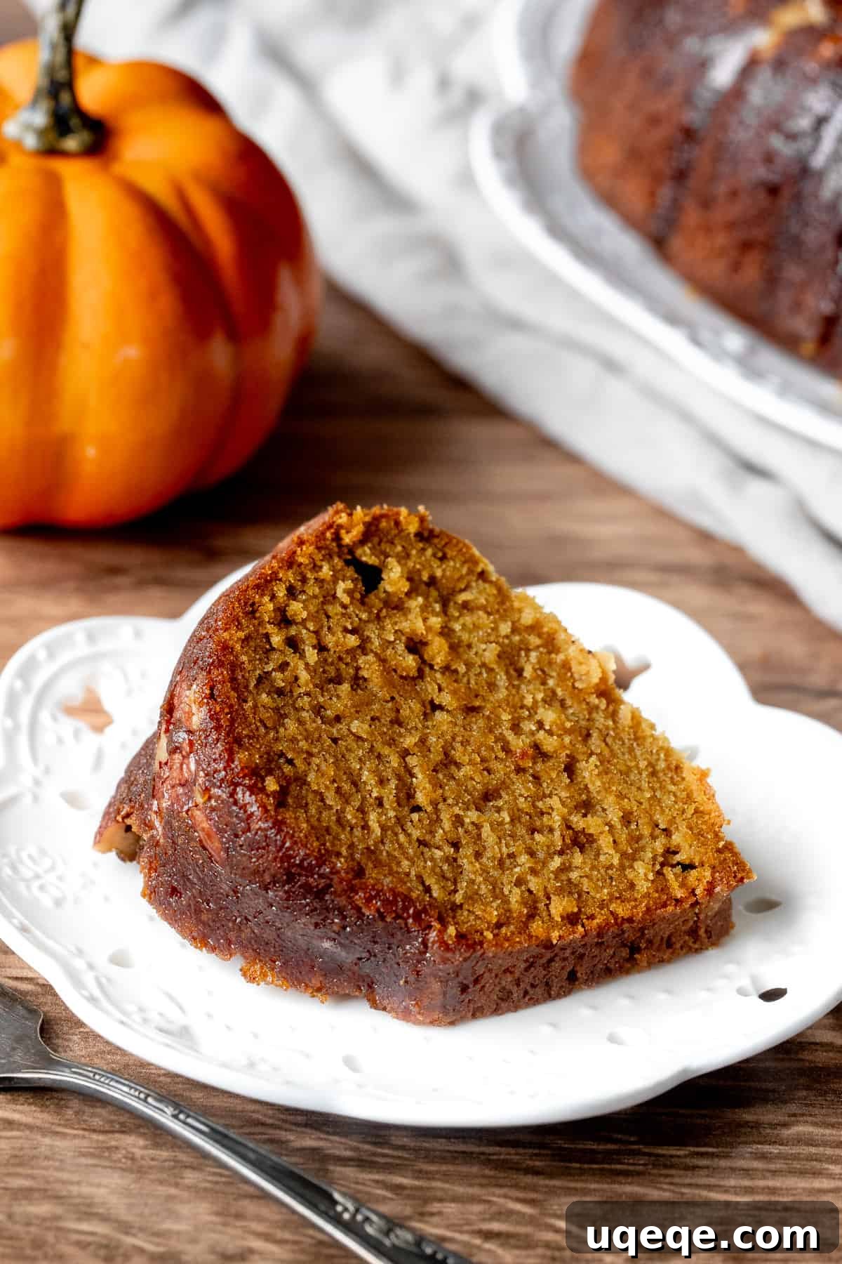 A delectable slice of pumpkin rum cake with butter rum glaze on a white plate, ready to be enjoyed.