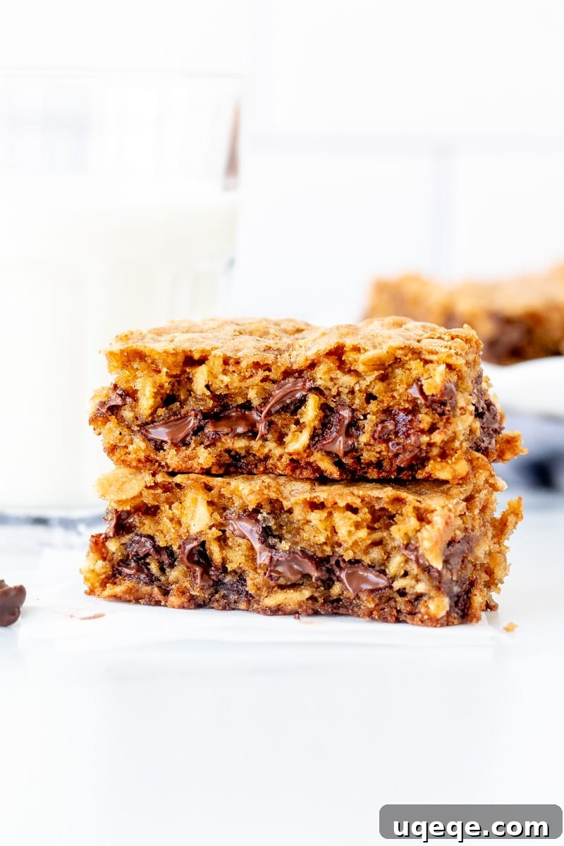 Chewy Oatmeal Chocolate Chip Bars 7 Oatmeal chocolate chip cookie bar broken in half, revealing gooey chocolate, next to a glass of milk