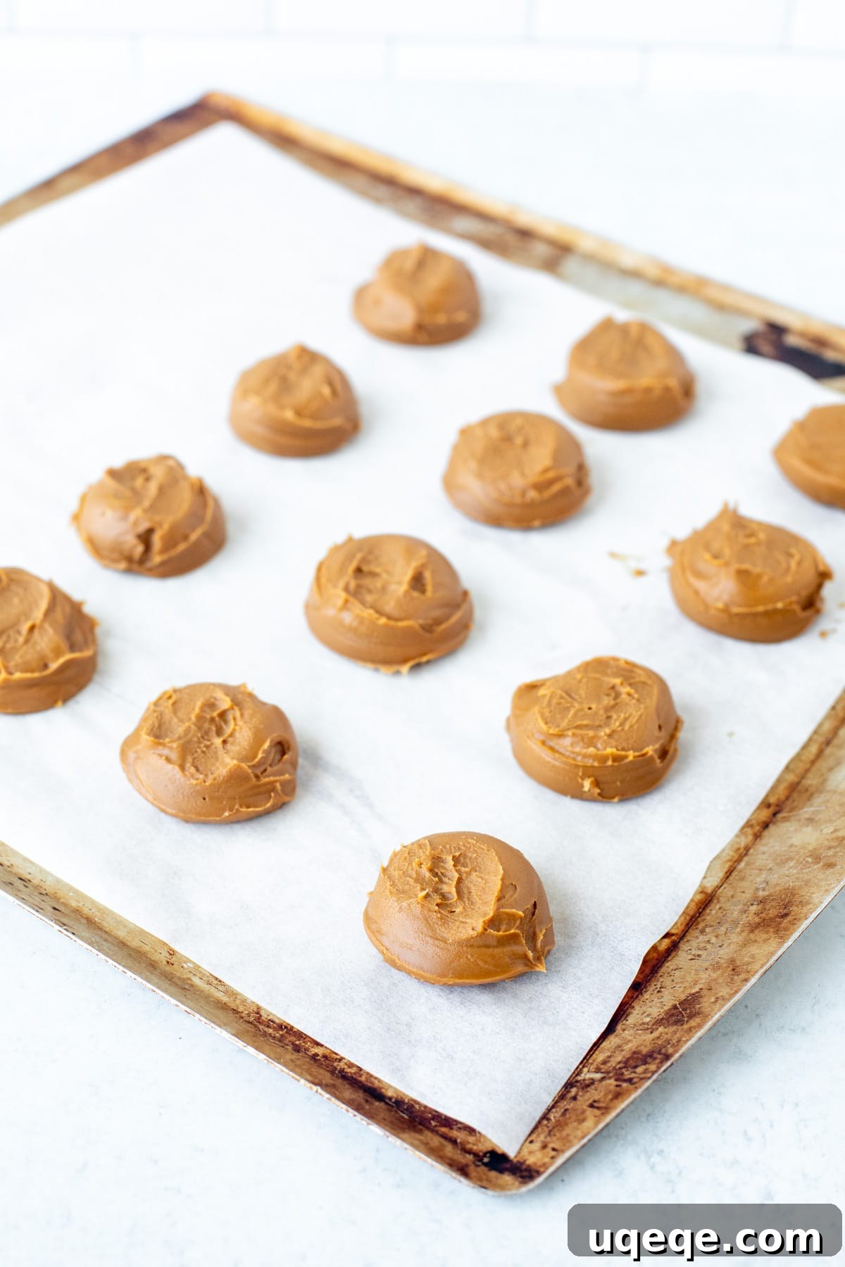 Biscoff Cookies Bursting with Cookie Butter 4 Spoonfuls of cookie butter on a lined cookie sheet ready for freezing.