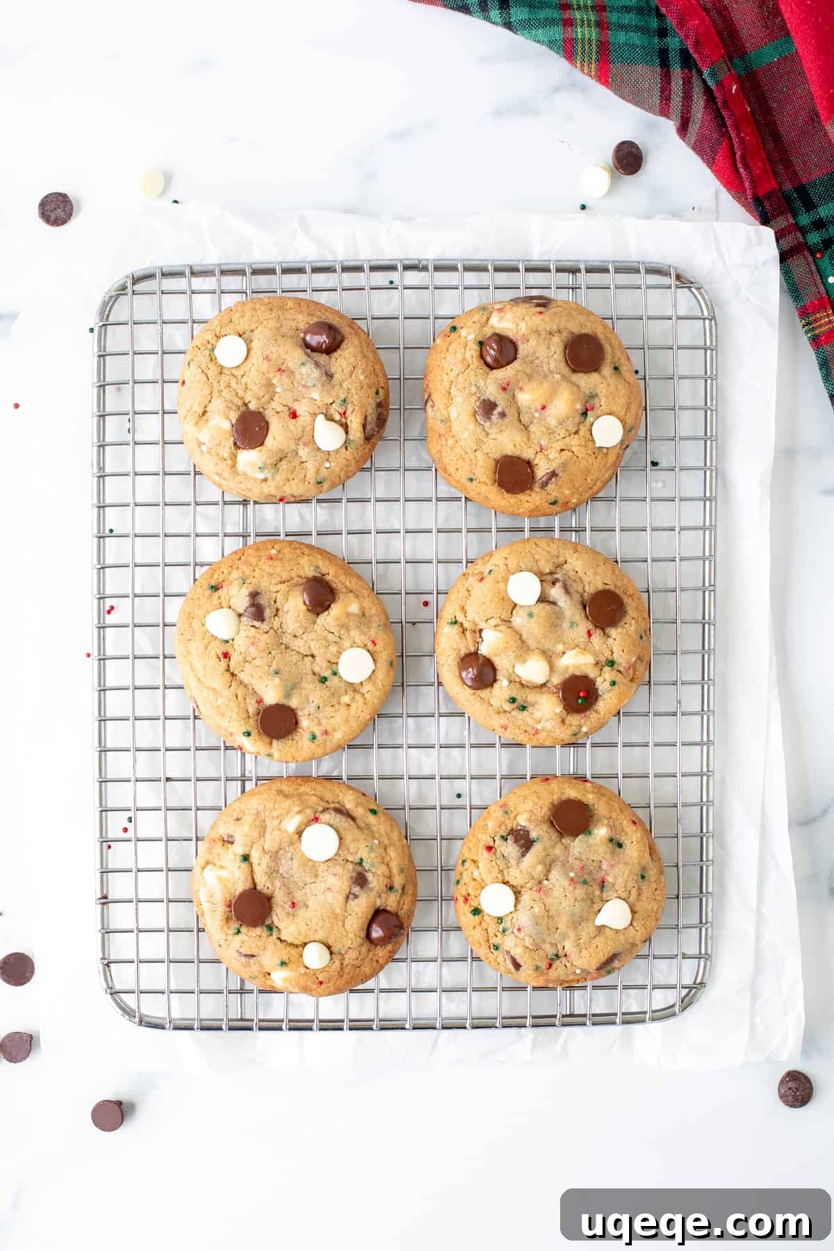 Freshly baked Christmas chocolate chip cookies cooling on a wire rack, glistening with melted chocolate.
