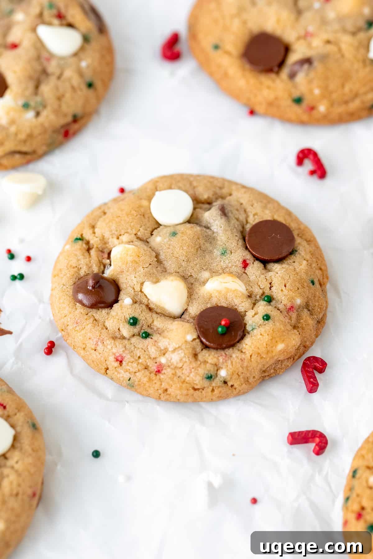 A close-up of a single perfect Christmas chocolate chip cookie, showcasing its rich chocolate chips, creamy white chocolate chips, and festive red and green sprinkles.