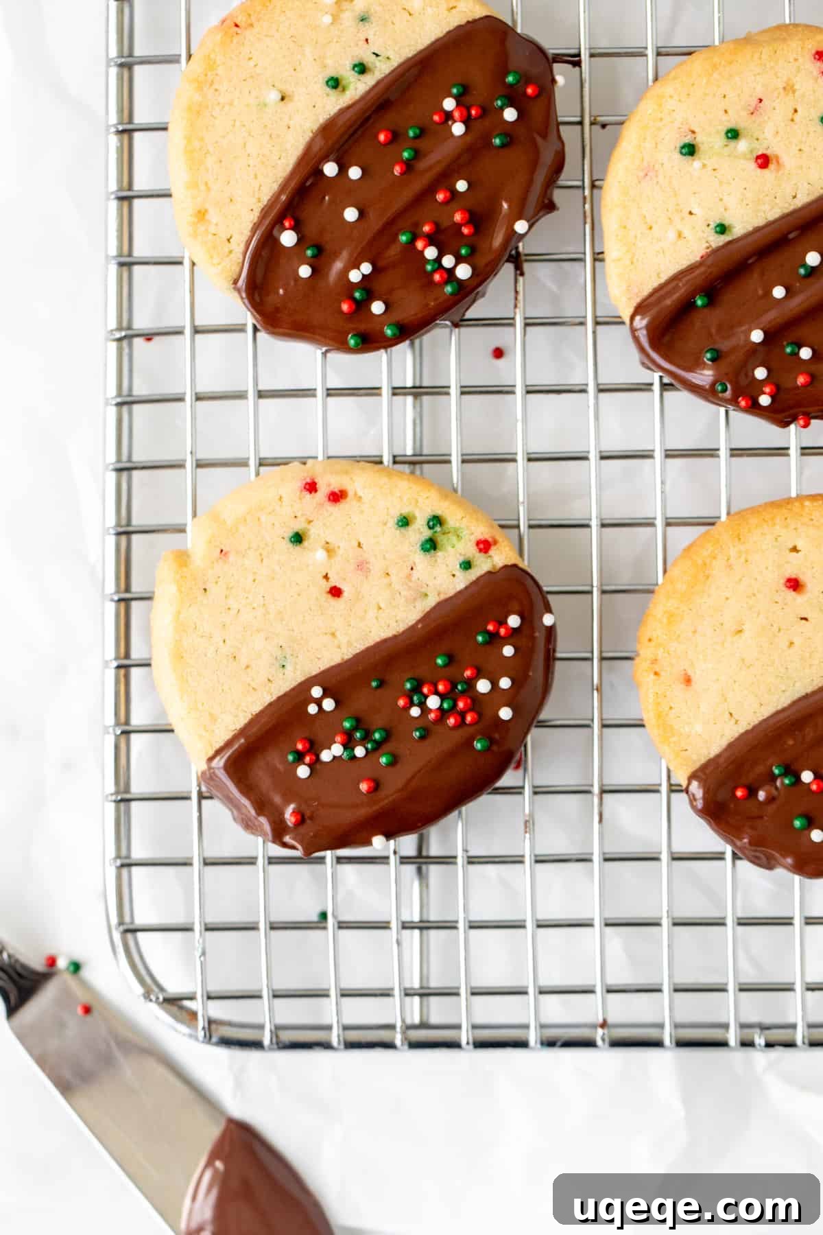 Holiday Sparkle Slice and Bake Cookies 3 Christmas sprinkle slice and bake cookies, half dipped in chocolate, cooling on a wire rack