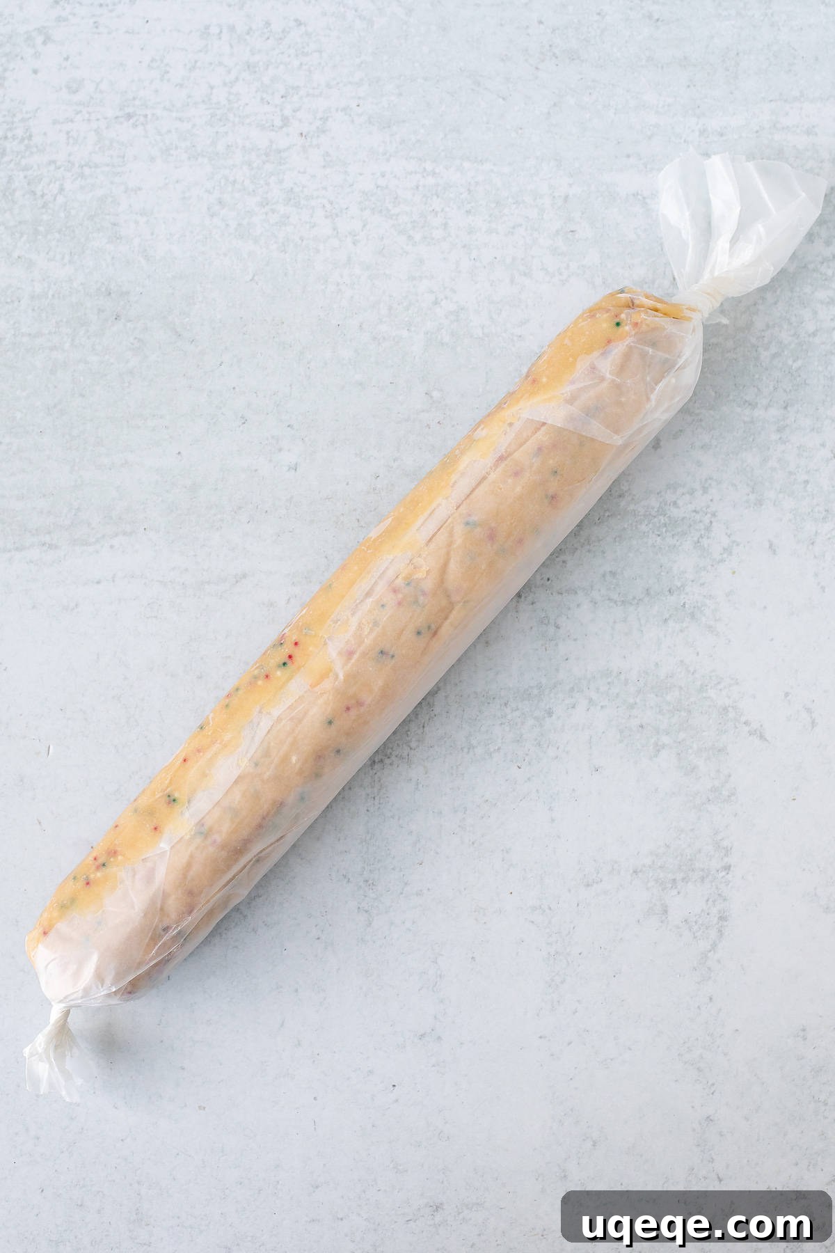 Holiday Sparkle Slice and Bake Cookies 4 Cookie dough log tightly wrapped in wax paper with twisted ends, ready for chilling