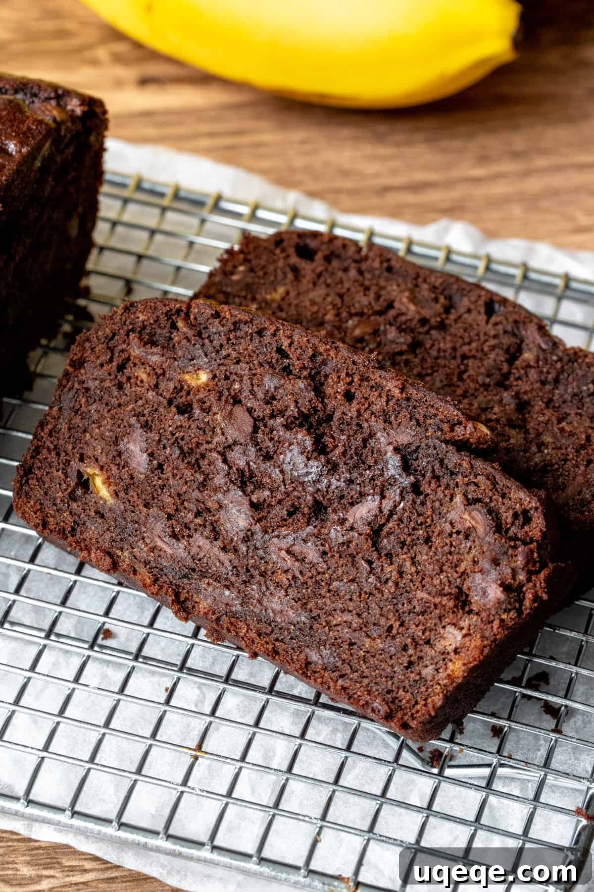 Decadent Double Chocolate Banana Bread 2 Two generous slices of rich, moist chocolate banana bread resting on a cooling rack, showcasing its inviting texture and abundant chocolate chips.