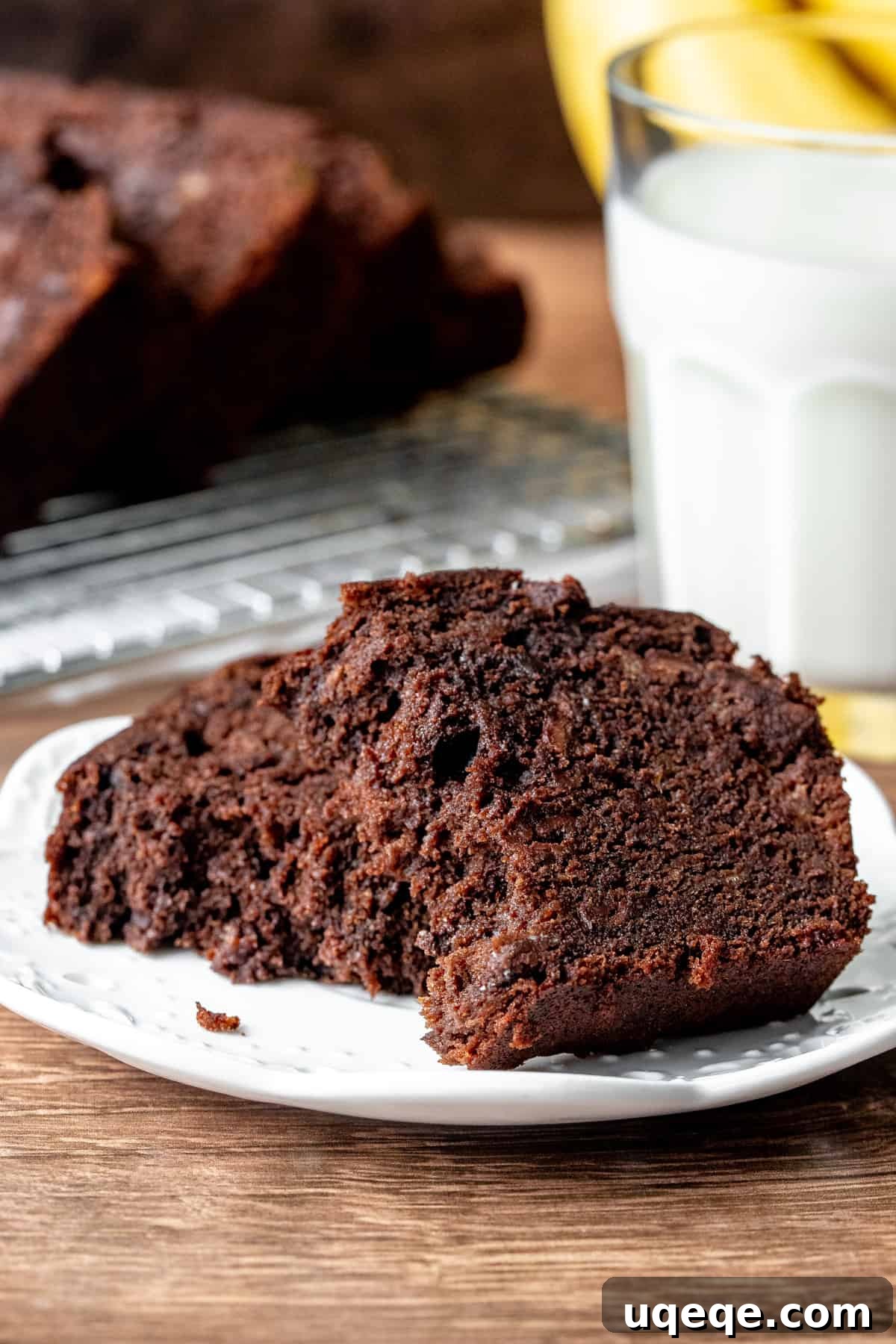 Decadent Double Chocolate Banana Bread 5 A delicate slice of moist double chocolate banana bread, gently pulled apart on a pristine white plate, showcasing its soft, rich interior texture.