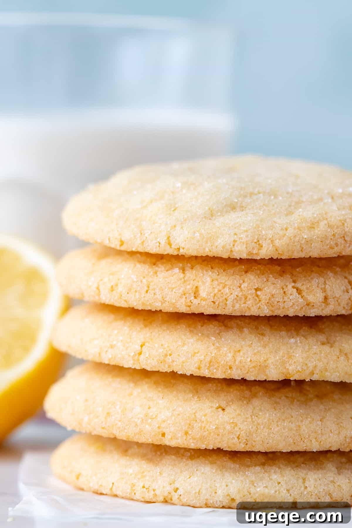 Zesty Lemon Delights 3 Stack of five golden lemon sugar cookies next to a glass of milk, emphasizing their deliciousness and ideal pairing.
