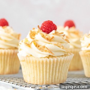 Coconut cupcakes with coconut frosting, decorated with toasted coconut on a cooling rack