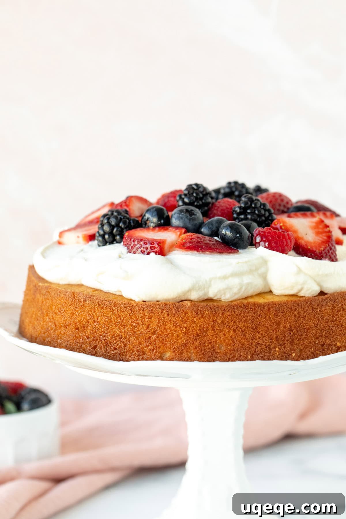 Velvet Berry Bliss Cake 2 A stunning Berries and Cream Cake adorned with fresh mixed berries, presented on a pristine white cake stand. The perfect, elegant summer dessert.
