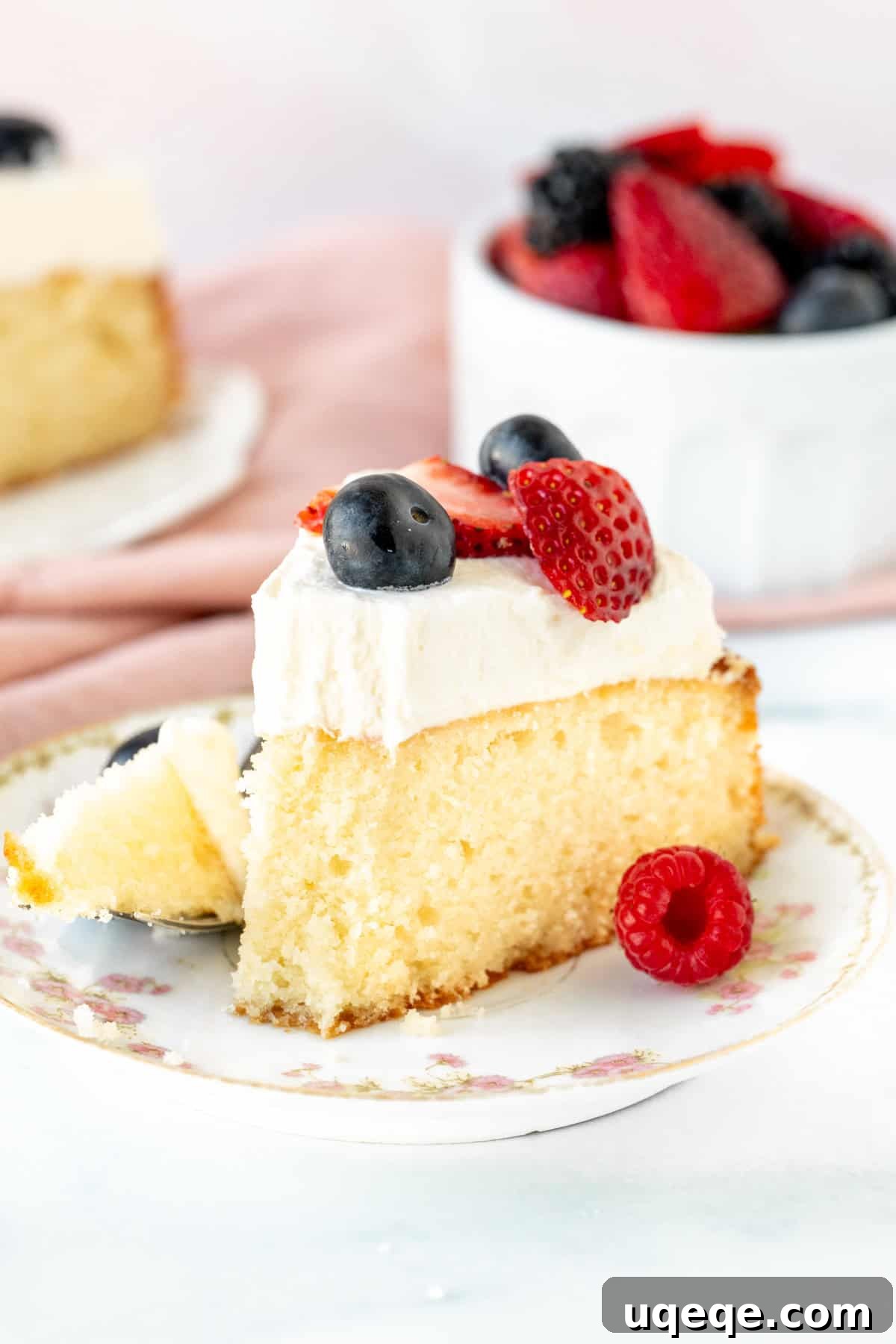 Velvet Berry Bliss Cake 9 A close-up of a slice of Berries and Cream Cake with a small bite taken out, highlighting its moist interior, creamy topping, and fresh fruit.