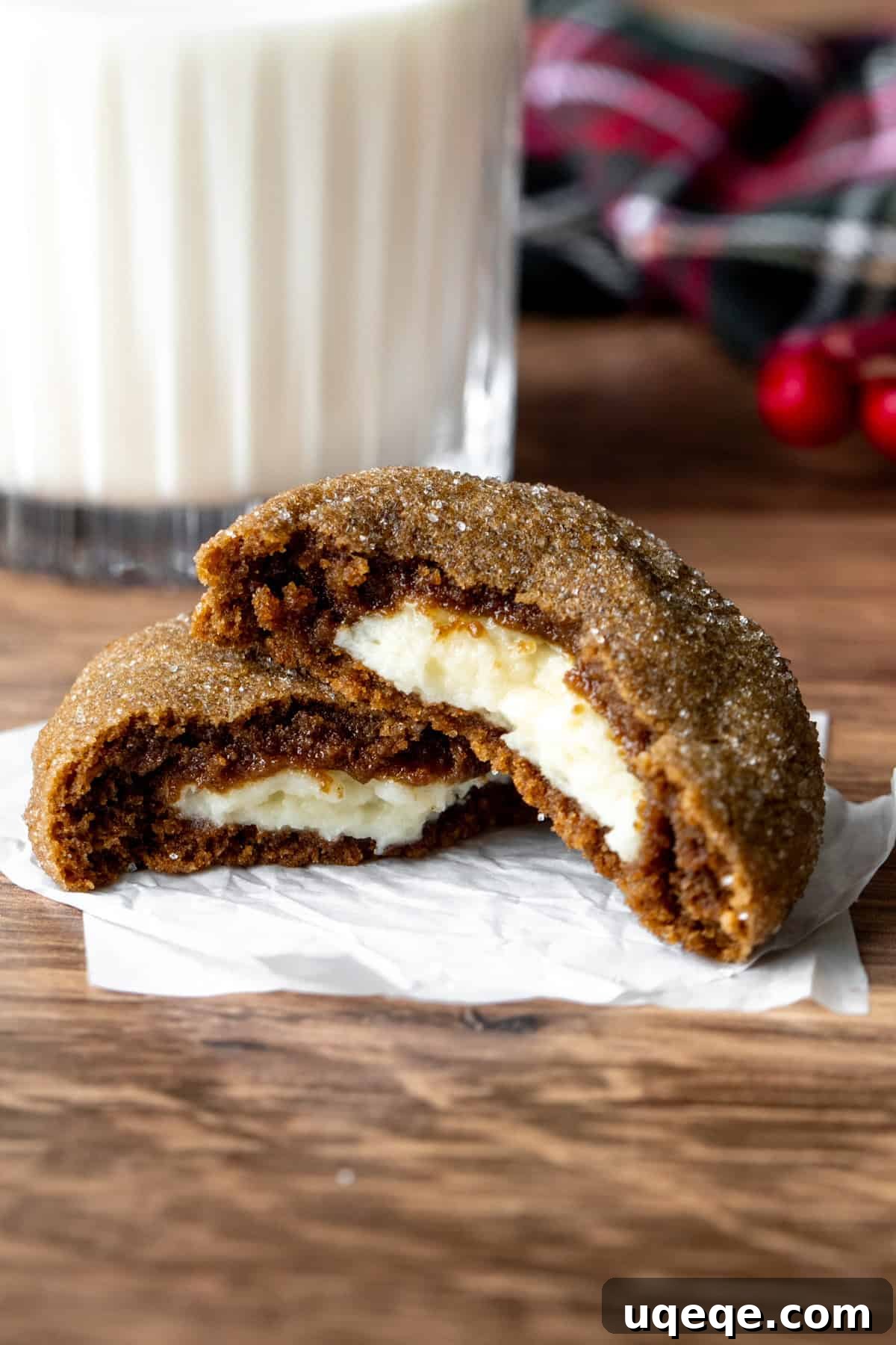 Gingerbread Cheesecake Delights 7 A warm gingerbread cheesecake cookie broken in half, revealing the soft filling, next to a glass of milk