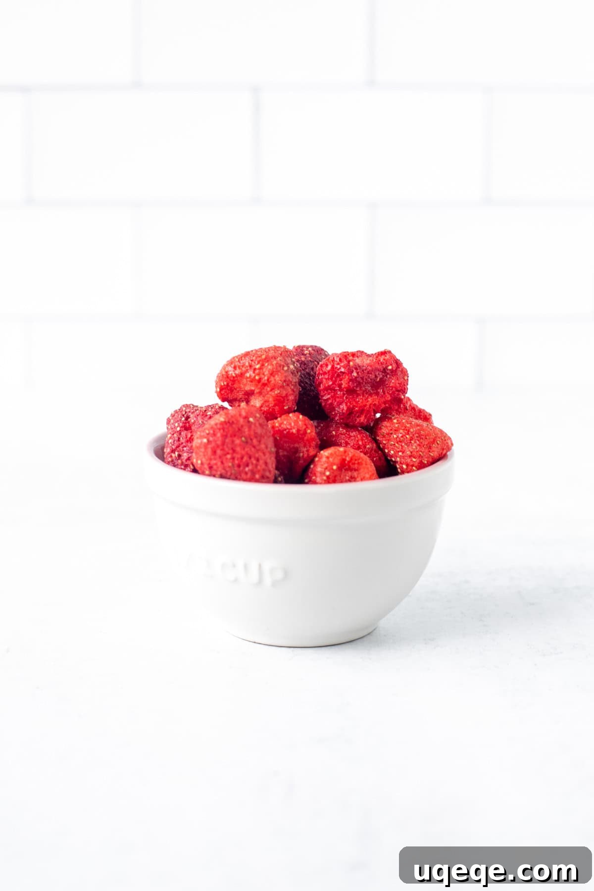 Rosy Strawberry Sugar Cookies 4 A small, elegant bowl filled with whole freeze-dried strawberries, showcasing their lightweight and airy texture. These berries are poised to be transformed into a flavorful powder for baking.