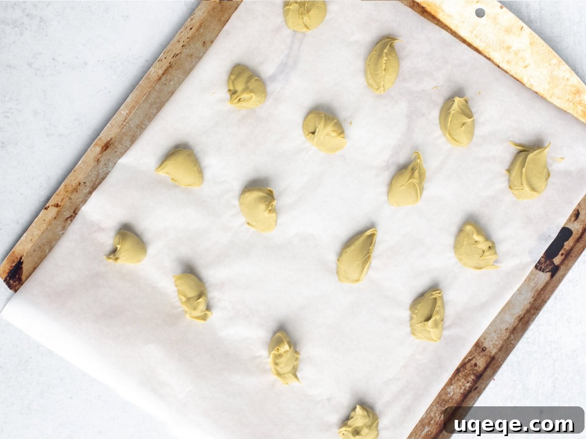 Pistachio Dream Chocolate Chip Cookies 4 Lined cookie sheet with individual frozen dollops of pistachio spread, ready for cookie assembly