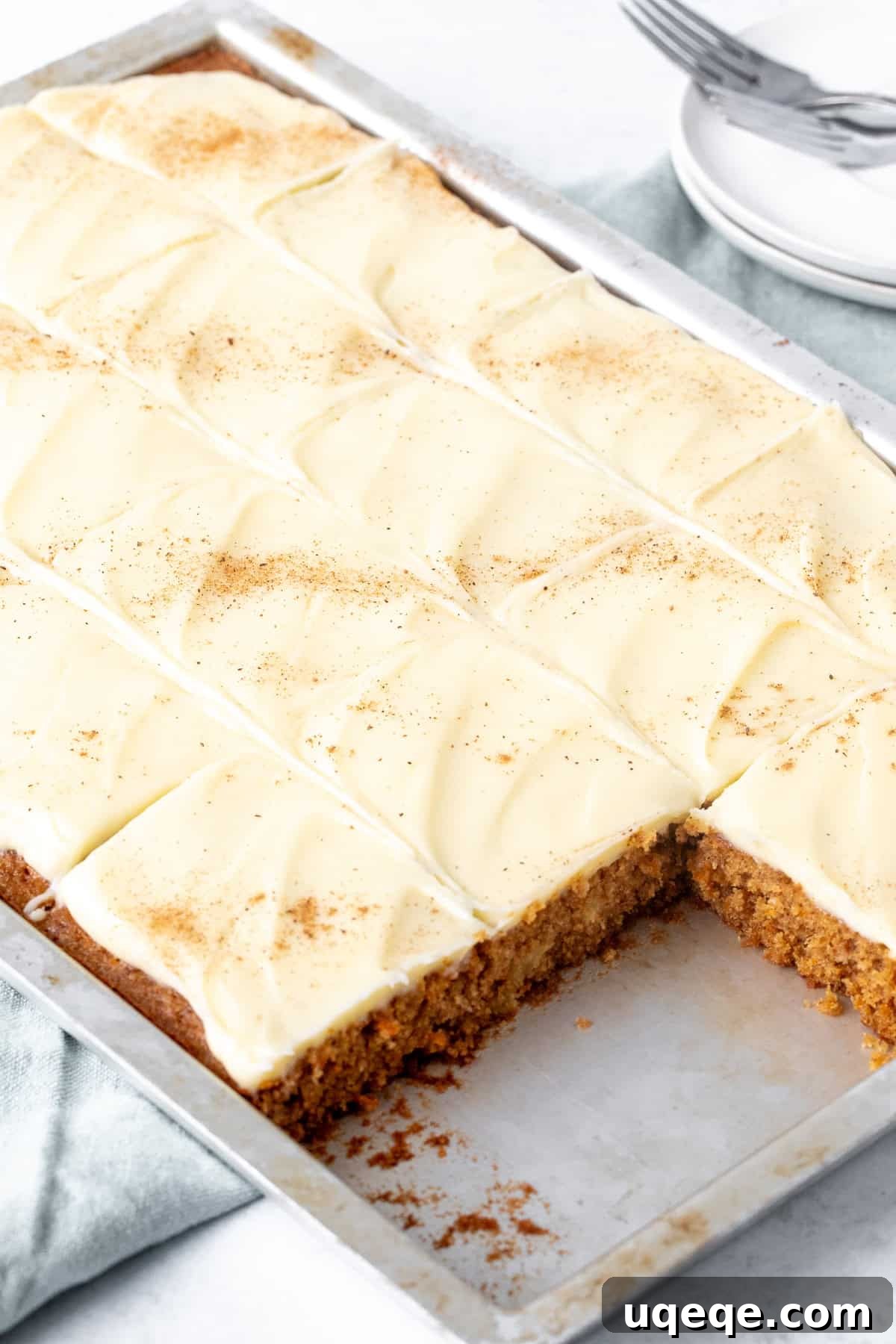 Spiced Carrot Cake Squares 3 A sheet pan filled with freshly baked carrot cake bars, generously slathered with rich cream cheese frosting and neatly cut into individual squares.