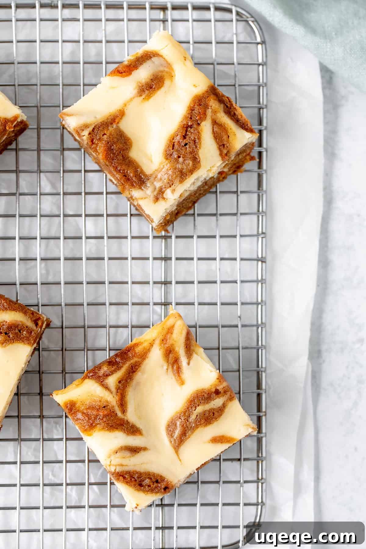 Spiced Carrot Cake Cheesecake Bars 8 Carrot cake bars swirled with cheesecake on a cutting board, neatly sliced and ready to serve.