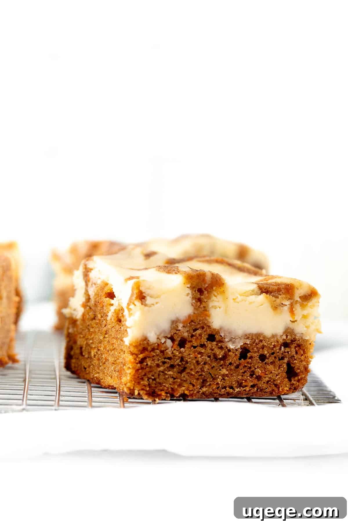Spiced Carrot Cake Cheesecake Bars 9 Swirled carrot cake cheesecake bars cooling on a wire rack, showcasing their inviting texture and professional finish.