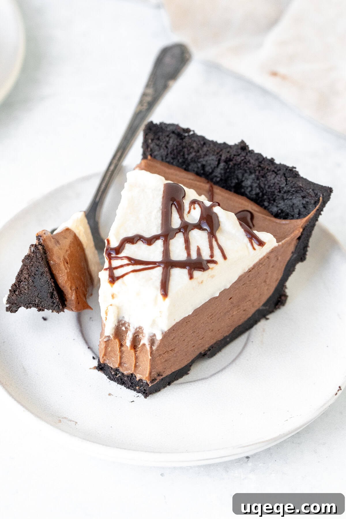 Decadent Nutella Pie 7 A delectable slice of No-Bake Nutella Pie, topped with whipped cream and a luxurious chocolate drizzle, showcasing its irresistible layers.
