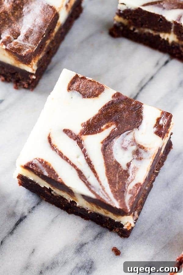 Swirled Cream Cheese Brownies 2 A close up shot of a fudgy, cream cheese brownie with elegant swirls of brownie and cheesecake, showcasing its rich texture.