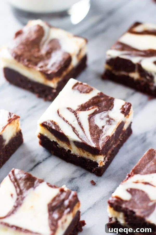 Swirled Cream Cheese Brownies 5 Cream cheese brownies with a distinct swirled cheesecake layer, perfectly cut into squares and arranged on a elegant marble background.