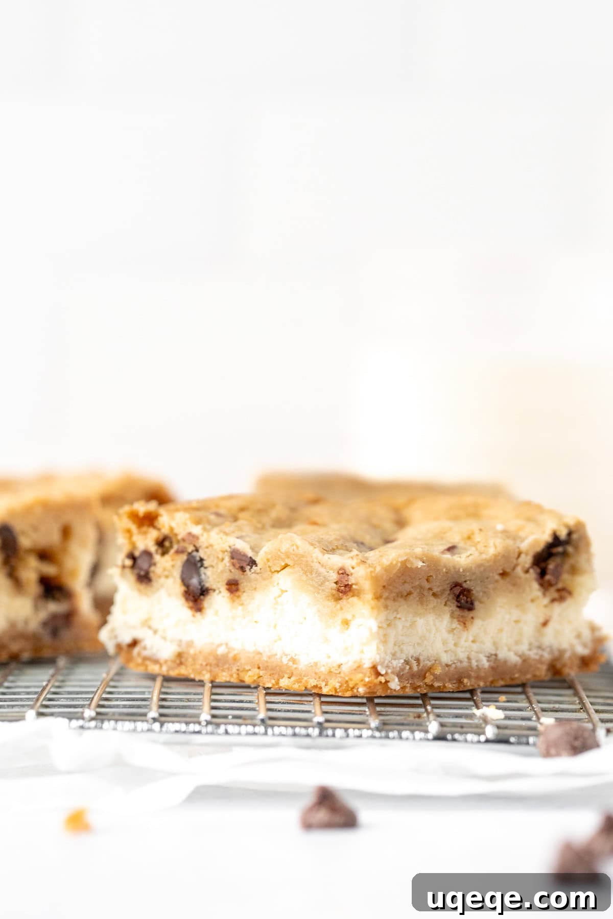 Heavenly Chocolate Chip Cheesecake Bars 4 A single chocolate chip cookie cheesecake bar resting on a cooling rack, showing its layers clearly