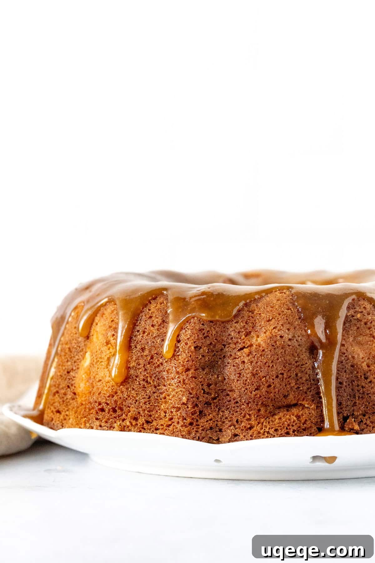 Autumn Apple Harvest Bundt 2 Beautifully baked Apple Bundt Cake topped generously with a rich caramel drizzle, ready to be served for a cozy fall treat.