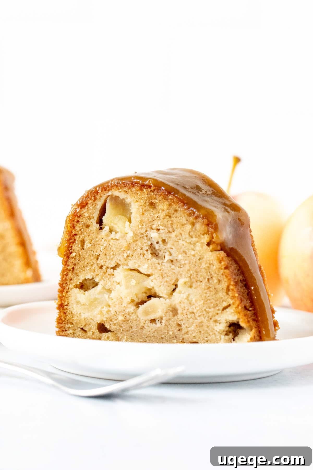 Autumn Apple Harvest Bundt 3 A delectable slice of apple bundt cake, revealing chunky apple pieces within its moist crumb, topped with a generous swirl of brown sugar sauce.