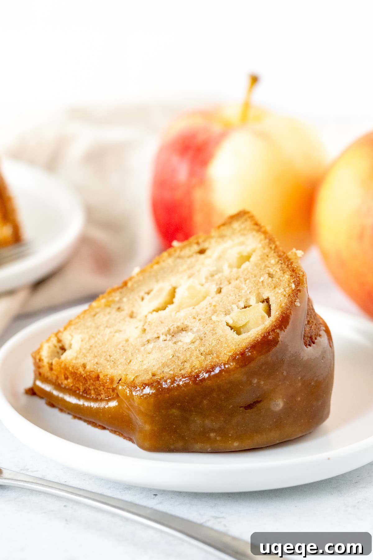 Autumn Apple Harvest Bundt 8 A close-up shot of a single piece of apple cake, freshly cut from a bundt pan and generously topped with a homemade caramel drizzle, ready to be enjoyed.