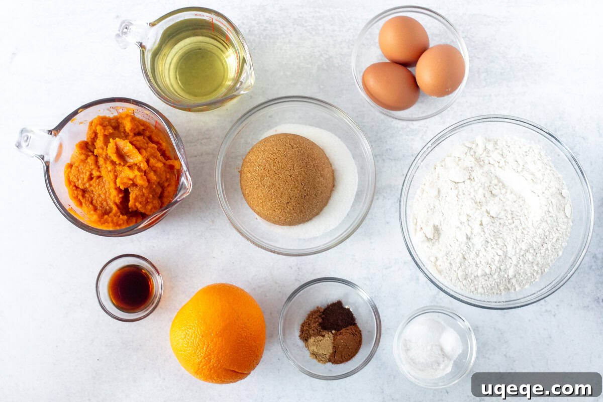 Warm Spiced Pumpkin Delight 5 A collection of fresh ingredients for pumpkin cake, including flour, spices, eggs, oil, sugars, pumpkin puree, and an orange for zest.