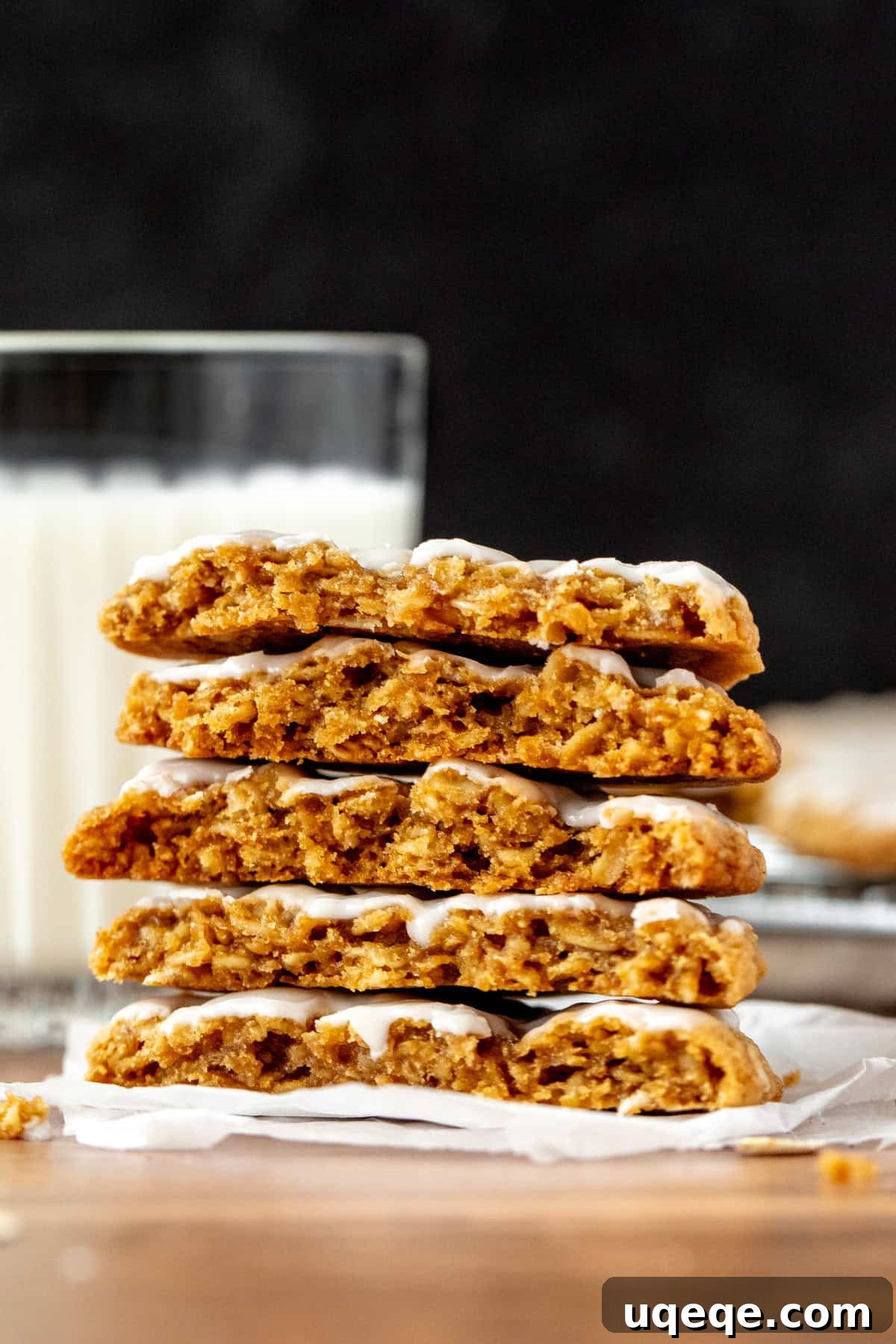 Glazed Oatmeal Delights 3 A stack of golden-brown iced oatmeal cookies, with one cookie broken in half to highlight its texture.