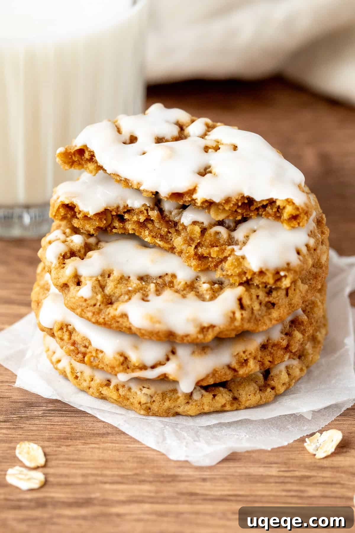 Glazed Oatmeal Delights 6 A stack of delicious iced oatmeal cookies, with the top cookie broken in half to reveal its tender interior.