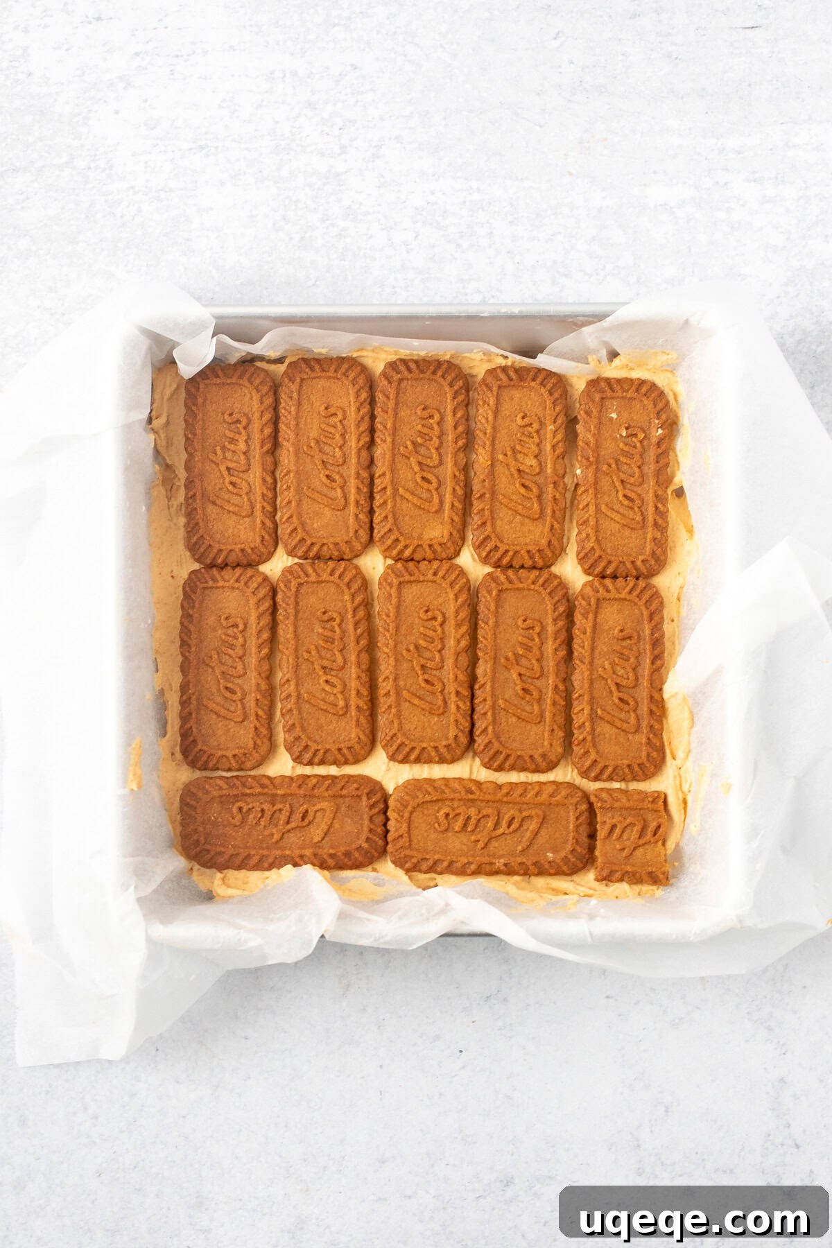 A step-by-step image showcasing the layering process of the pumpkin icebox cake, with cookies and creamy filling being placed into a square pan.