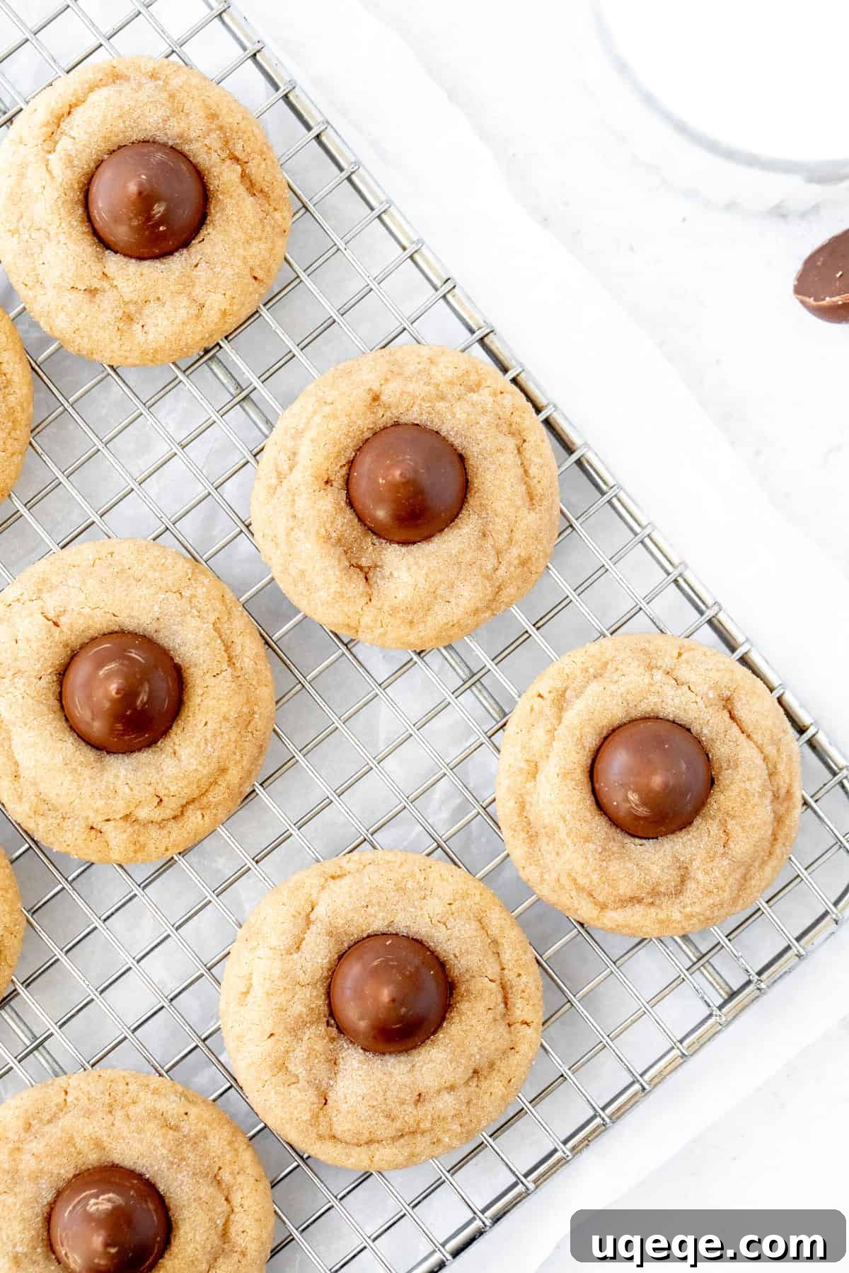 Peanut Butter Bliss Bites 7 A batch of shiny, perfectly round peanut butter blossoms cooling on a wire rack, showcasing their texture and chocolate tops.