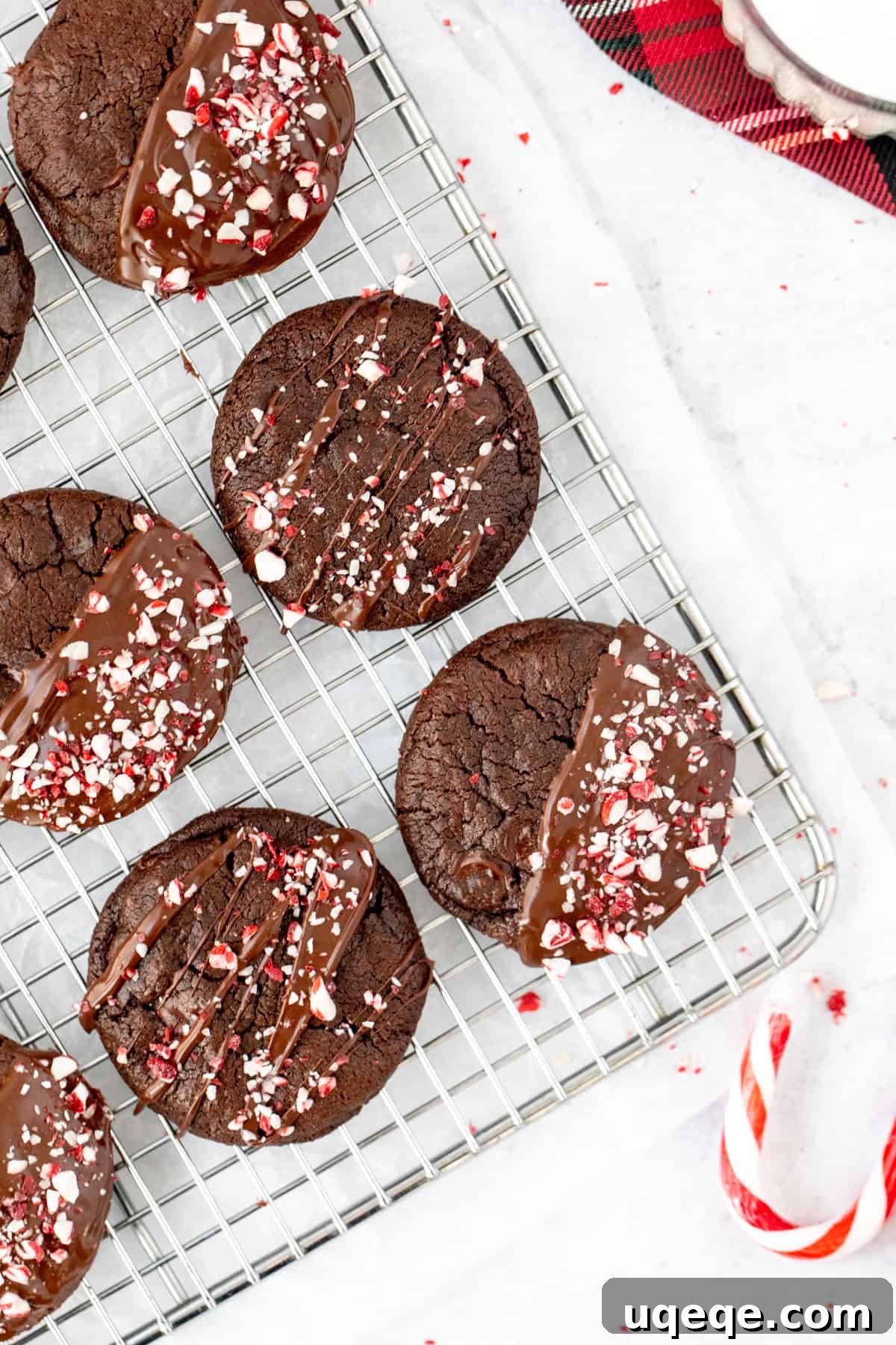 Chewy Double Chocolate Peppermint Delights 5 chocolate peppermint cookies on a cooling rack, topped with chocolate and crushed candy canes.
