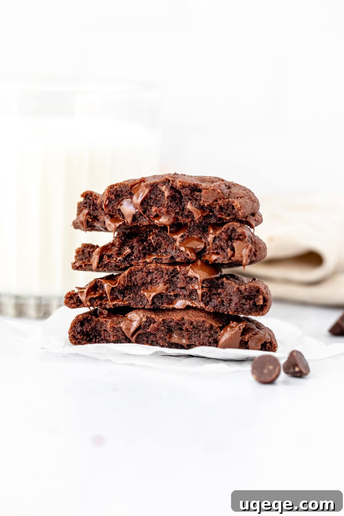 Two rich, fudgy double chocolate cookies broken in half and elegantly stacked, revealing their gooey chocolate chip centers.