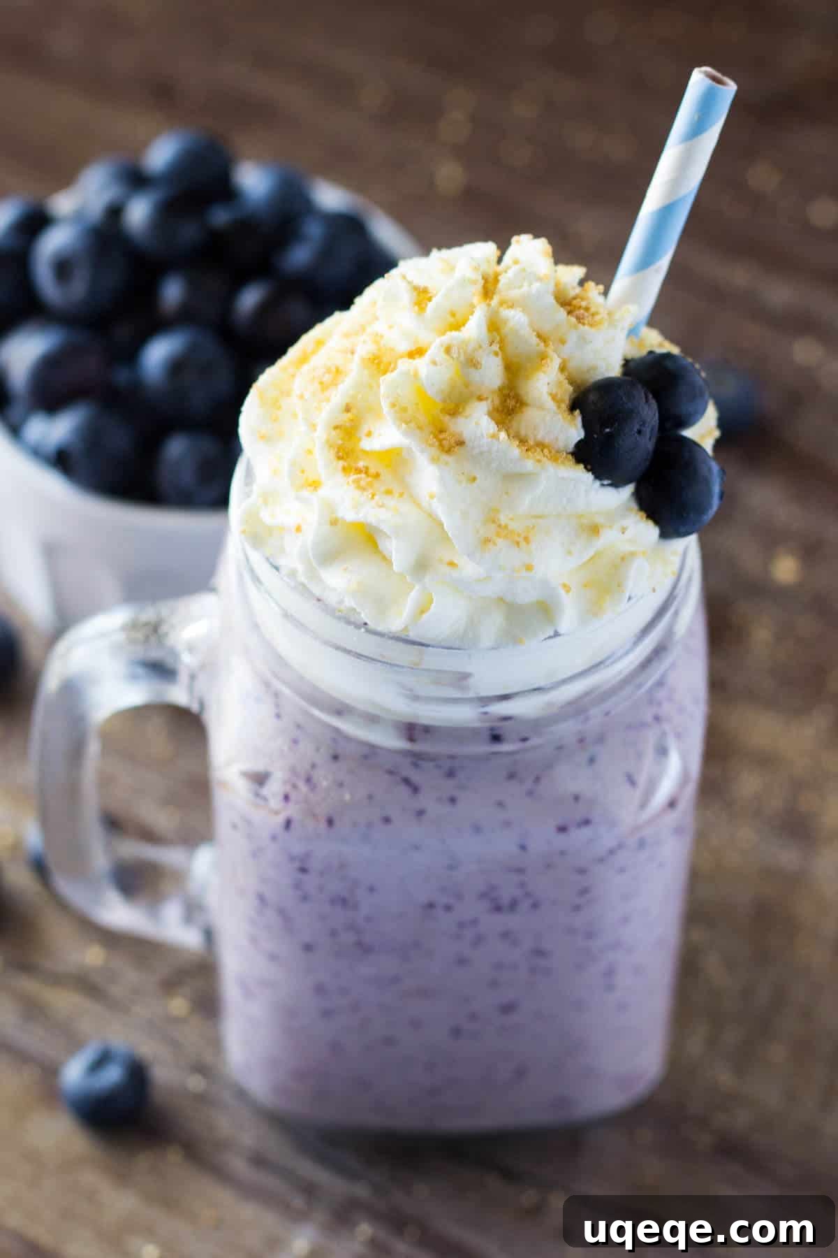 Velvet Blueberry Cheesecake Dream 2 A tall glass of super thick and creamy Blueberry Cheesecake Milkshake topped with whipped cream and graham cracker crumbs, ready to be enjoyed on a hot day.