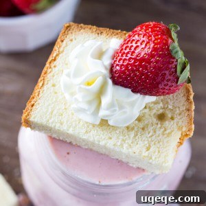Close-up of a Strawberry Shortcake Milkshake in a tall glass, garnished with whipped cream and a strawberry.