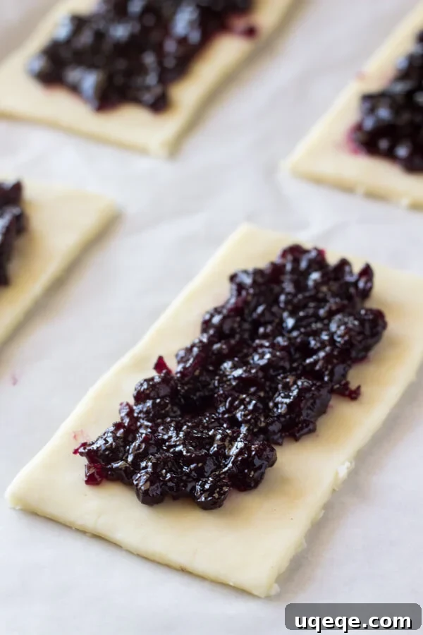 Flaky Homemade Blueberry Toaster Strudels 4 Assembling homemade blueberry toaster strudels with blueberry filling and egg wash.