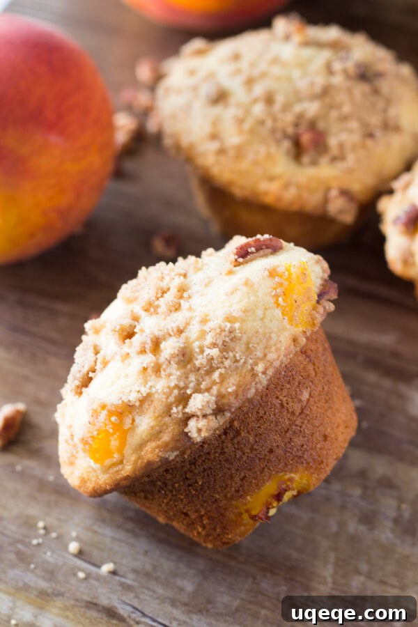 Golden Peach Crumble Muffins 3 Fluffy, buttery, super soft Peach Muffins with Streusel Topping - The combo of fresh summer peaches and crunchy, cinnamon, pecan streusel makes these the perfect peach muffins!