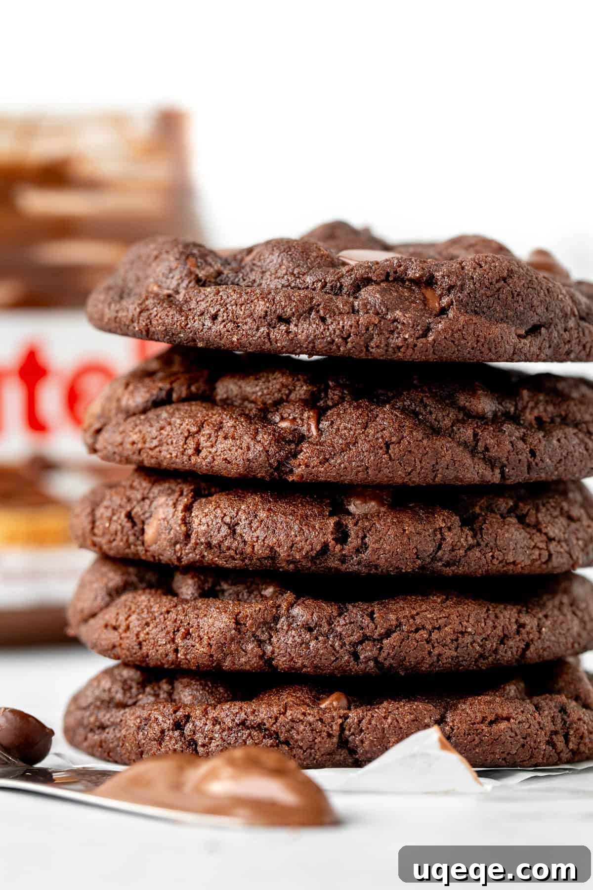 Irresistible Nutella Cookies 2 Stack of soft and chewy Nutella chocolate cookies with a jar of Nutella in the background, highlighting their delicious chocolate hazelnut flavor and perfect texture.