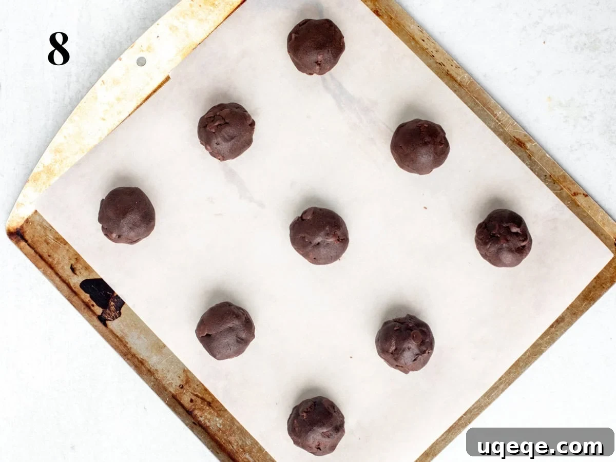 Irresistible Nutella Cookies 6 Lined cookie sheet with perfectly scooped Nutella cookie dough balls, spaced evenly for baking.