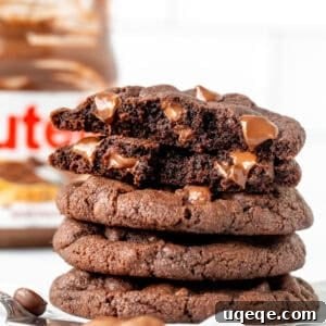 Irresistible Nutella Cookies 9 Nutella chocolate chip cookies stacked on top of each other with the top cookie broken in half, showing the chewy interior.