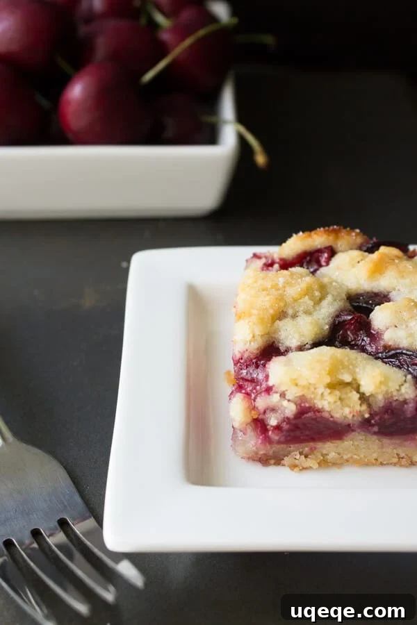 Golden Cherry Almond Squares 2 Delicious Cherry Almond Bars on a cooling rack, showcasing the golden crumb topping and ruby red cherry filling – the perfect summer fruit bars.