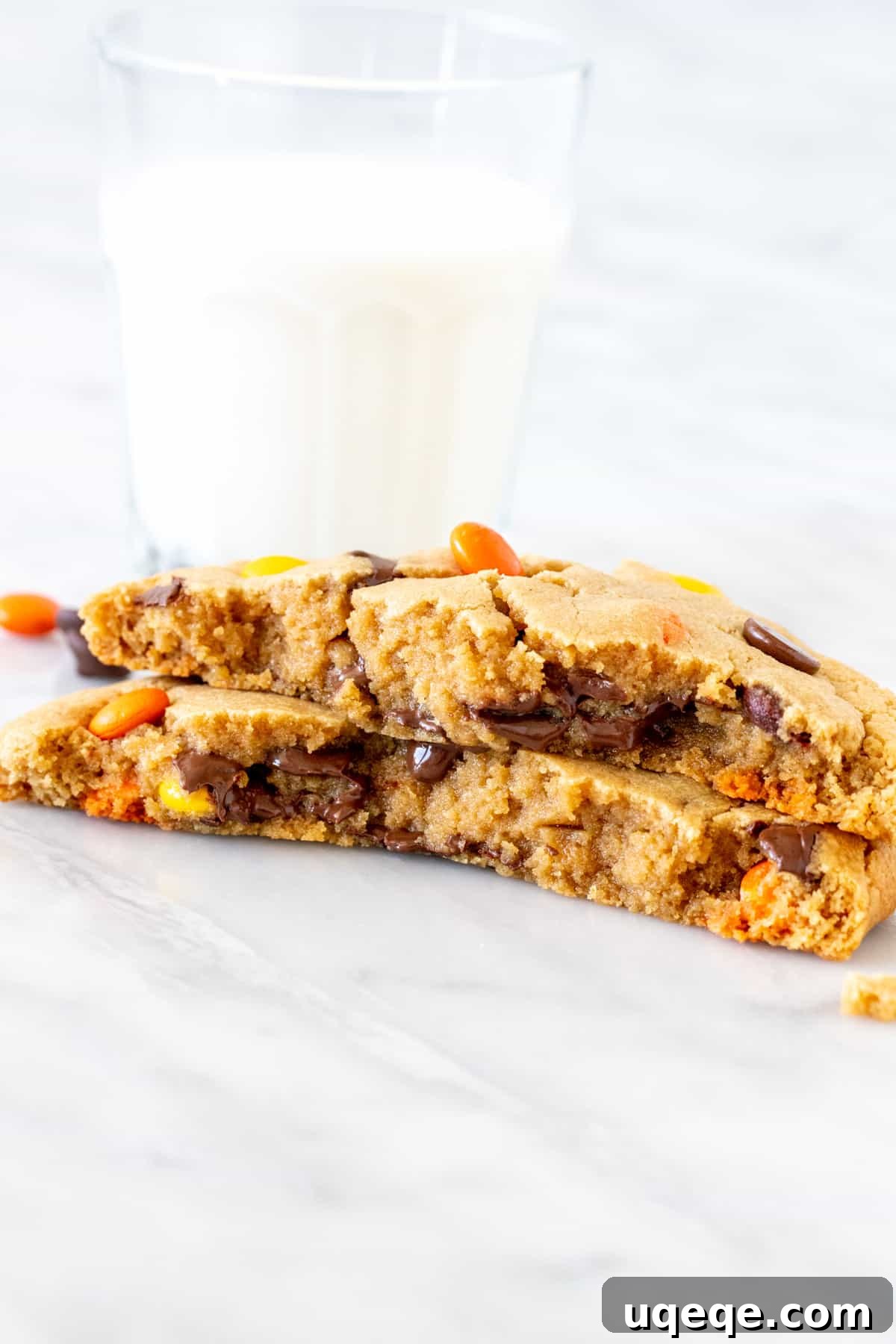Easy Solo Peanut Butter Cookie 5 A single serving peanut butter cookie, thick and inviting, broken in half to reveal its thick, soft, and gooey center, generously studded with melted chocolate chips and colorful Reese's Pieces.