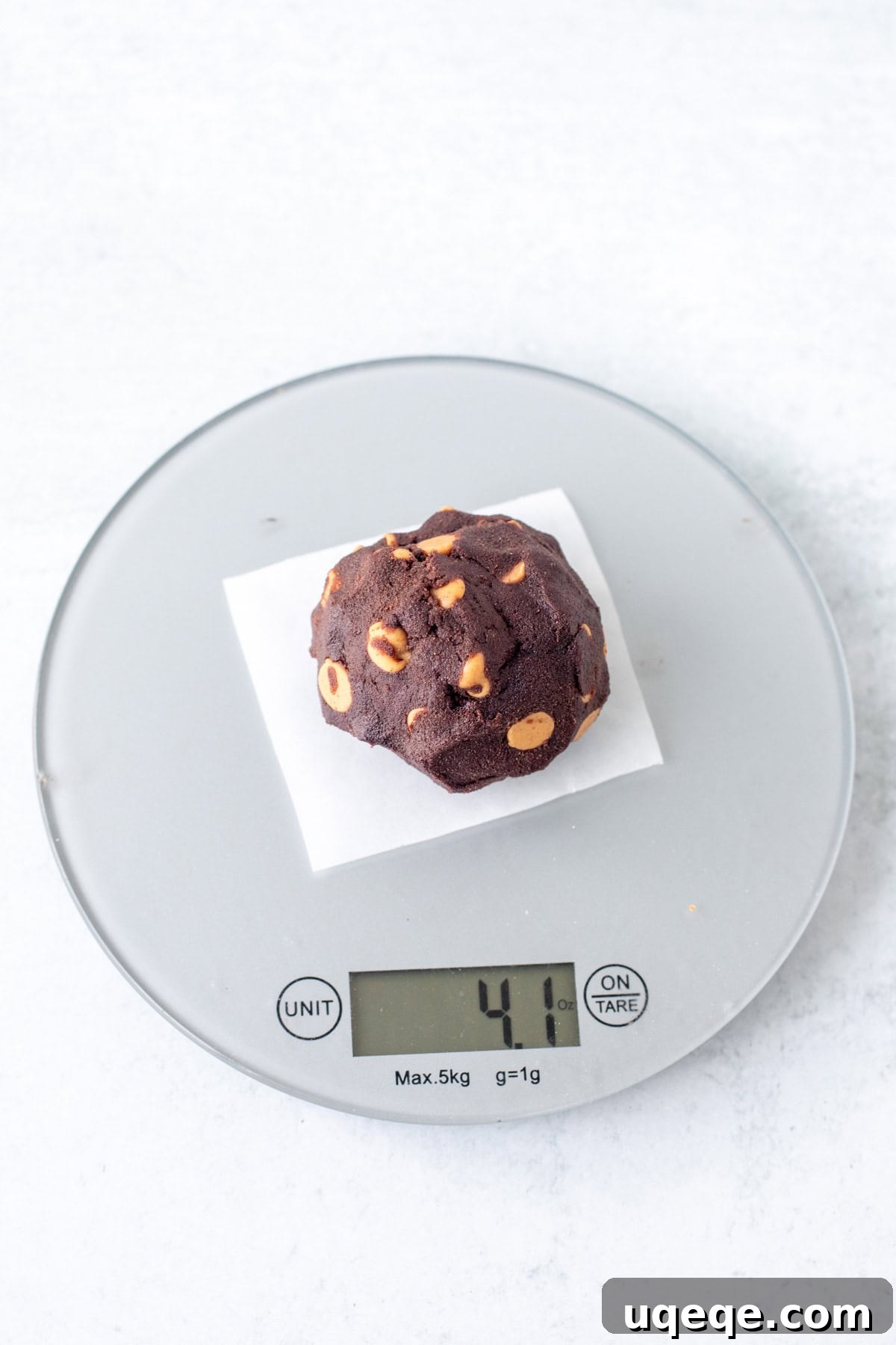 Peanut Butter Dark Chocolate Chip Delights 4 A large ball of dark chocolate peanut butter chip cookie dough resting on a digital kitchen scale, perfectly portioned for baking.