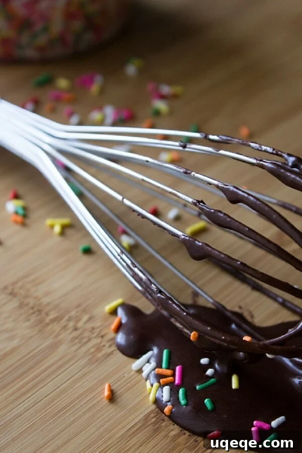 A whisk with chocolate glaze that's perfect for dipping chocolate doughnuts in.