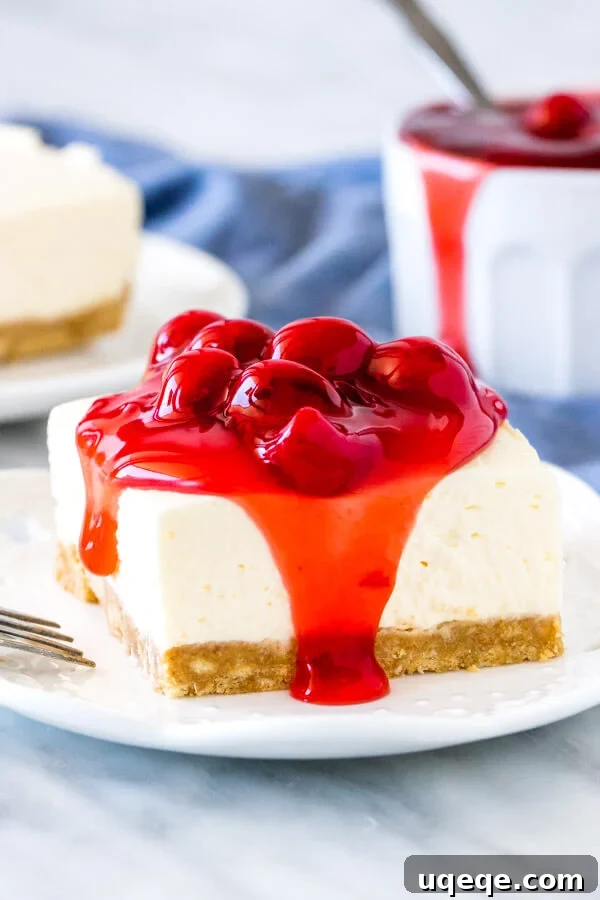 Luscious Chilled Cherry Bars 2 A perfectly sliced no-bake cherry cheesecake bar, revealing creamy layers and a crunchy crust, topped with glistening cherry pie filling.