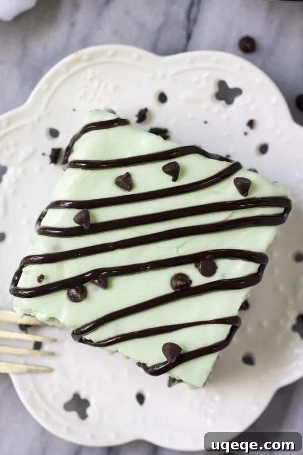 Effortless Mint Chip Ice Cream Cake 3 Overhead shot of a square slice of mint chip ice cream cake drizzled with chocolate sauce on a white plate