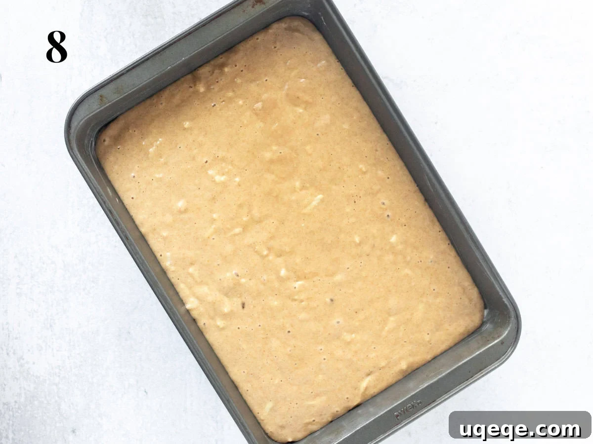 Orchard Spice Cake with Cream Cheese Cloud 9 A pan filled with unbaked apple spice cake batter, ready to be placed in the oven.