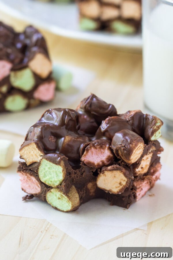 Funfetti Chocolate Delights 5 Soft, chewy chocolate confetti square with a bite taken out of it. Second confetti square and glass of milk in the background.