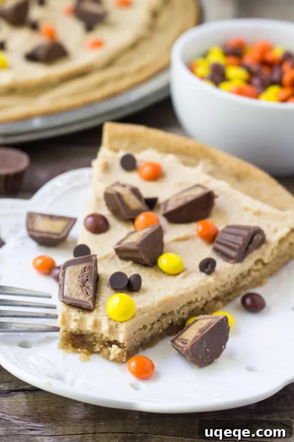 Slice of peanut butter cookie pizza with a soft and chewy peanut butter cookie base, peanut butter frosting and peanut butter candies.