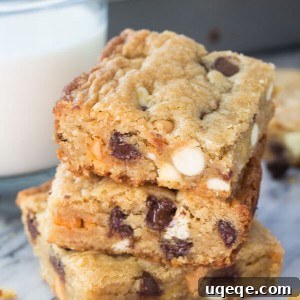 Triple Chocolate Chip Dream Bars 6 Side shot of 3 stacked triple chip cookie bars with a glass of milk and the cookie bar pan in the background.